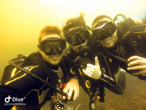 Maxime along with two other divers deep in the water, smiling at the camera